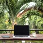 A laptop placed on the table with the green trees in background